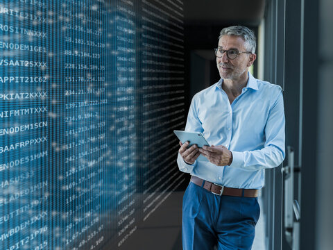 Businessman analyzes digital data on tablet in modern office