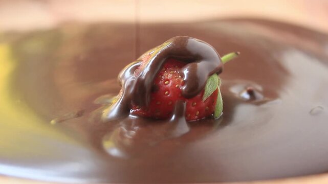 pouring melted chocolate over a strawberry