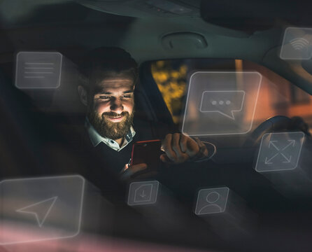 Smiling man uses mobile AI chatbot in a car at night