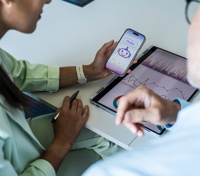 Woman shows a chatbot on a smartphone to a man in the office