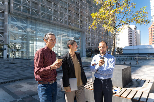 Business team drinking coffee and talking at an outdoor office plaza