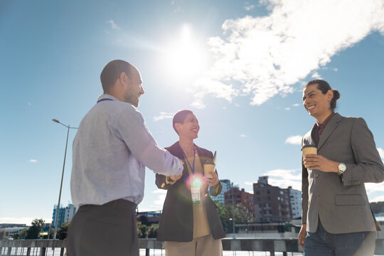 A businessman and businesswoman shake hands outdoors in the city