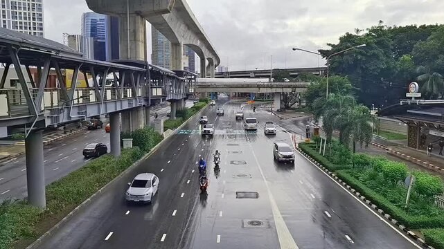 Vehicles Driving On Wet Urban Main Road Under Elevated Train Track Structure In City
