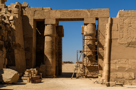 Ancient Egyptian temple gateway with carved hieroglyphs and restoration scaffolding