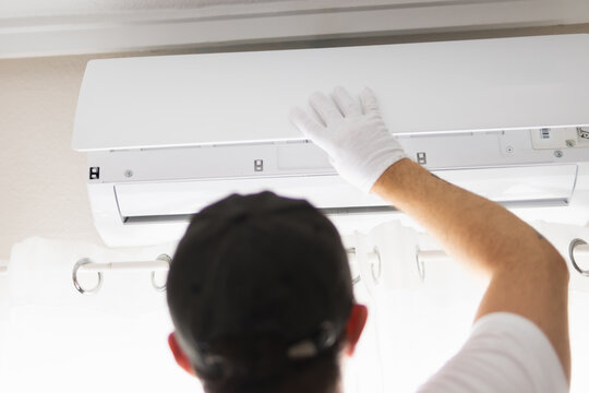 Technician in protective glove providing expert air conditioner repair and maintenance service, ensuring optimal cooling performance and clean air quality indoors