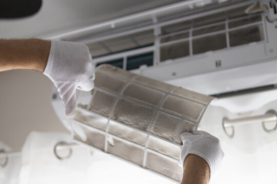 Technician wearing white gloves pulls a severely clogged ac filter, highlighting urgent maintenance to restore airflow, efficiency and healthier indoor air quality for homes
