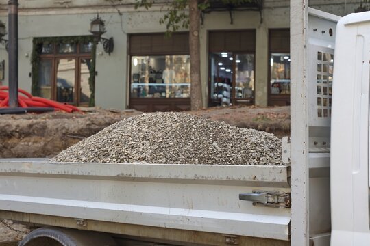 Pile of gravel inside truck bed at urban road construction site
