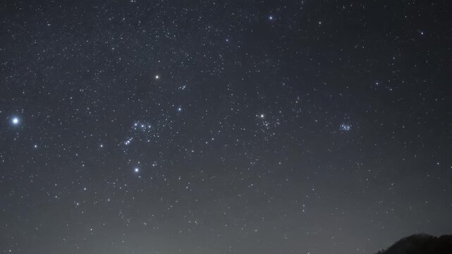 Starry Night Sky with Orion Constellation and Sirius Above Mountain Ridge