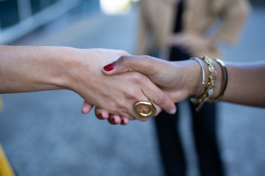 Two African American and white people shaking hands outdoors