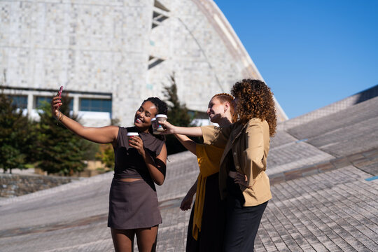 African American and white women taking selfie with coffee cups