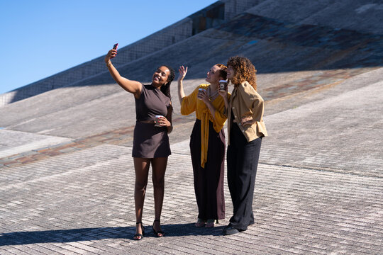 Three African American and white women taking selfie outdoors