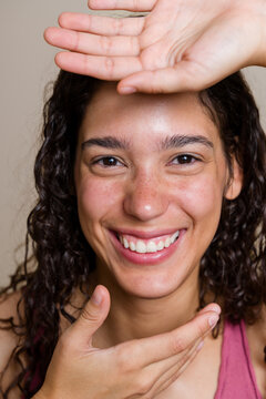 Hispanic woman smiling with hands framing her face in beauty shoot