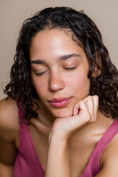 Portrait of a Hispanic woman with closed eyes resting hand on chin