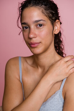 Portrait of Hispanic woman with natural skin against pink background