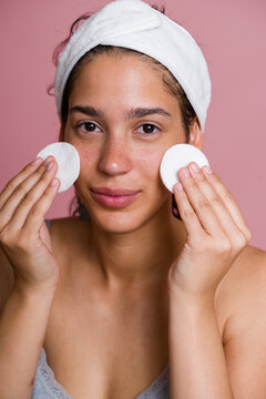 Hispanic woman cleansing face with cotton pads in beauty routine