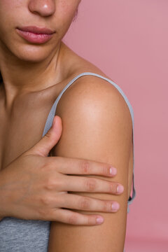 Hispanic woman touching shoulder showcasing smooth skin