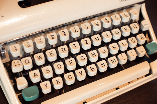 Close-up vintage manual typewriter keyboard with teal shift keys on wooden desk