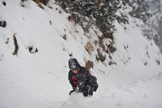 Boy playing in deep snow during heavy snowfall