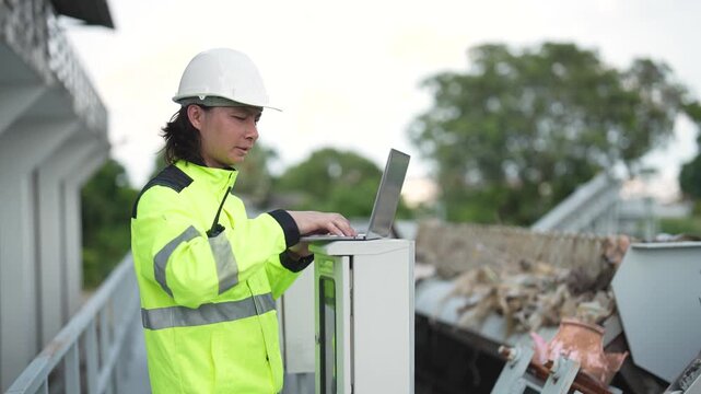 Engineer operates control cabinet while using walkie talkie to coordinate inspection and check water management equipment at water gate facility.