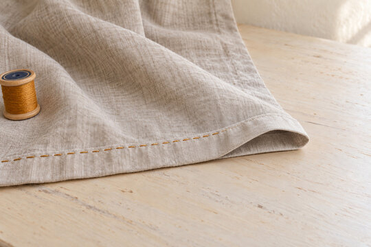 Partially stitched linen curtain hem beside a thread spool