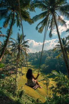 Photograph of a woman swinging on a wooden swing in a tropical jungle with rice fields in Bali.