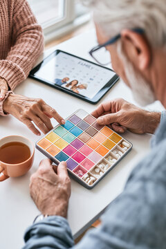 A caregiver helping an older adult organize weekly medications in a modern, color-coded pill organizer.