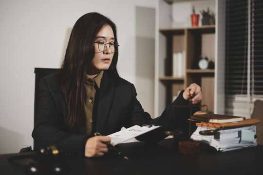 female lawyer in suit at workplace with laptop, gavel and femida in office