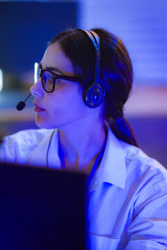 An operator checks the account while the caller waits while the headset mic sits close to her face during a focused late-night working session with the rest of the team nearby
