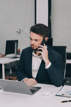 Two partners, team of professional business people working, discussing, writing notes at desk. Mature focused senior mentor leader man showing young woman manager project on laptop in modern office