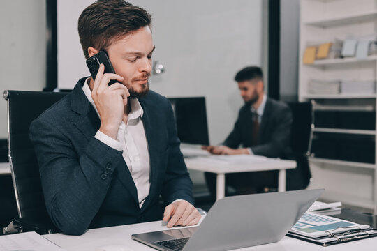 Two partners, team of professional business people working, discussing, writing notes at desk. Mature focused senior mentor leader man showing young woman manager project on laptop in modern office