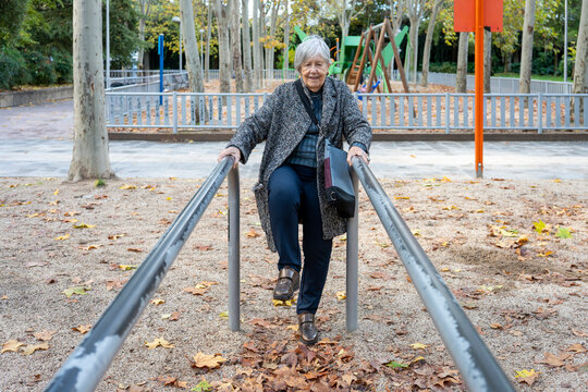 Senior woman exercising outdoors on parallel bars in park