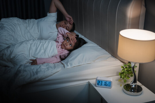 tired mother and preschool child girl having trouble sleeping in bed late at night, insomnia concept