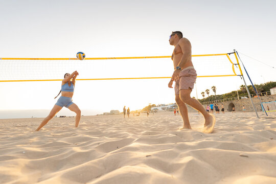 Enjoying a game of volleyball on the beach during sunset with friends