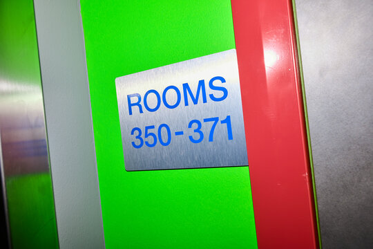 Close-up of a numbered sign mounted on a hallway wall, indicating the location of rooms within a colorful hotel.
