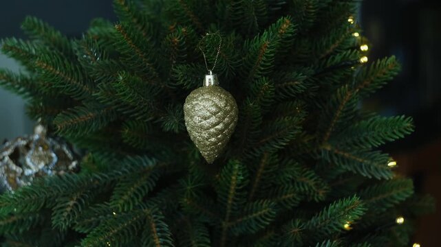 Preparing for winter Christmas holidays. Person hanging golden baubles on Christmas tree.