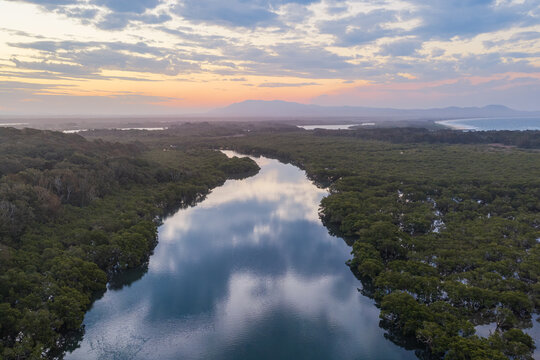 Aerial view along Back Creek at South West Rocks, New South Wales, during sunset, with calm water reflecting the colourful evening sky and surrounding mangrove landscape.