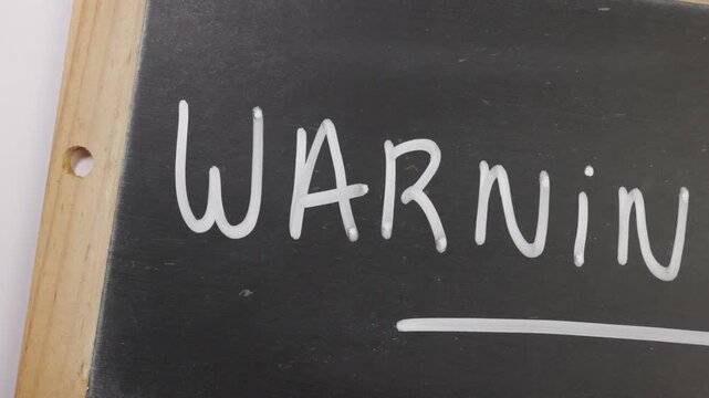 Avertissement &eacute;crit en anglais sur une ardoise noire