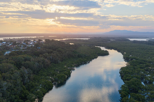 Aerial view across Back Creek and its surrounding mangrove landscape towards the coastal town of South West Rocks and distant mountains in New South Wales, Australia.