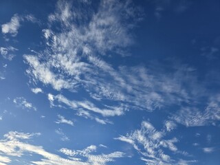 Wispy white cirrus clouds drifting across a deep blue sky © 고구마치킨너겟