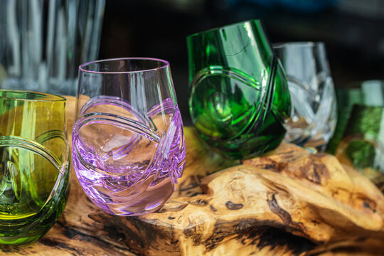 Elegant crystal glasses in green and pink colors displayed on a wooden surface in bright natural light