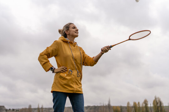 Woman badminton active hitting shuttlecock enjoying outdoor sports game on cloudy afternoon