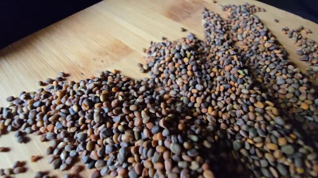 Creative arrangement of organic arugula seeds spread across a textured wooden background, showcasing natural patterns and rich details for gardening and agriculture concepts.   