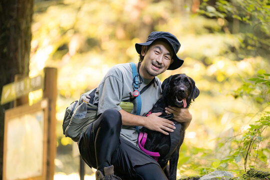 [晩夏～秋イメージ]愛犬と登山を楽しむ日本人男性、犬とのハイキング、アウトドア、トレッキング、自然の中を一緒に旅するペットとの休日