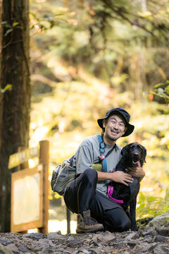 [Late Summer to Fall Theme] A Japanese man enjoying a mountain hike with his dog; hiking with a dog; outdoor activities; trekking; a vacation traveling through nature with a pet