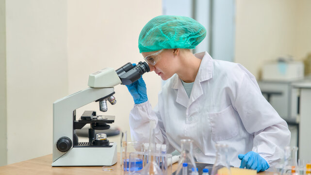 Woman scientist in a laboratory using a microscope for research, conducting an experiment, studying biology and chemistry, developing medicine, working in a science room