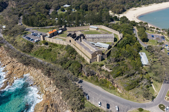 Aerial view of Laggers Point featuring the historic Trial Bay Gaol, rugged coastline, turquoise ocean and forested mountains near South West Rocks, New South Wales, Australia.