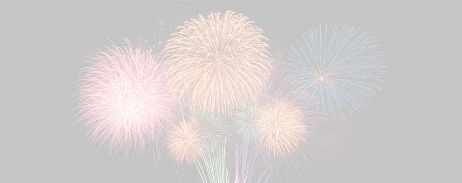 Multiple colorful fireworks explode in the night sky creating large spherical bursts of red, orange, blue, and green. The display features a dense arrangement with vibrant glowing trails.