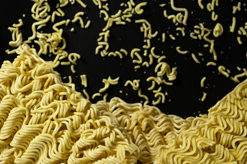Obraz premium Instant noodle brick next to scattered dry crumbs on black backdrop