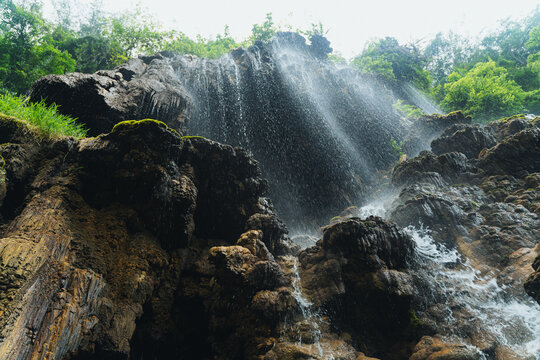 Waterfalls cascading down dark rocky cliffs covered in lush tropical foliage in Java Indonesia