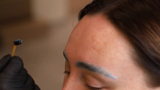 close up woman eyebrow threading with cotton swab and black glove
